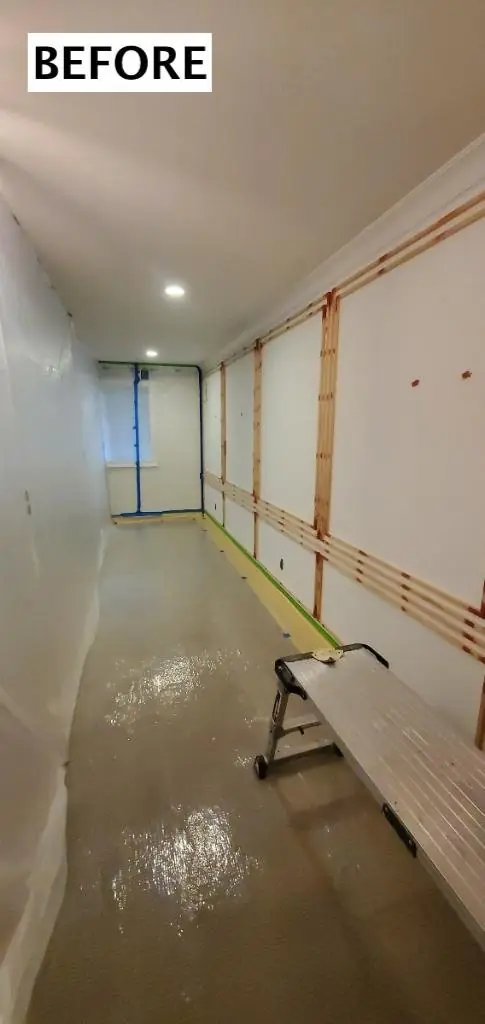 Hallway before painting: bare wood panel strips on a light wall, edges taped, floor covered